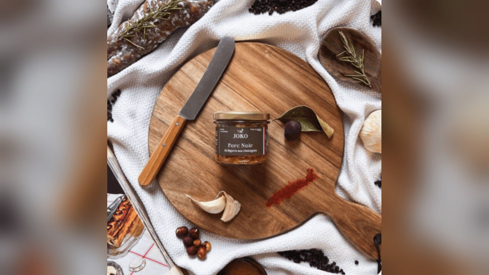 Le pot de terrine de porc noir de Bigorre aux châtaignes JOKO posé sur une planche en bois