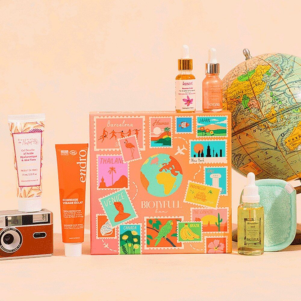 La Biotyfull Box d’octobre 2026 aux motifs de timbres du monde, entourée de ses produits et d’un globe
