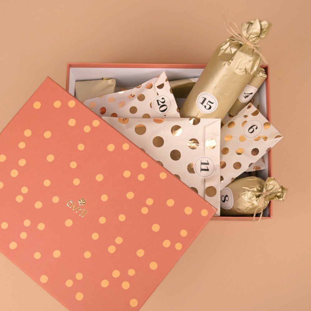 Le coffret du calendrier de l’Avent Avril 2026 ouvert, avec ses pochettes numérotées en papier kraft à pois dorés et ses papillotes dorées