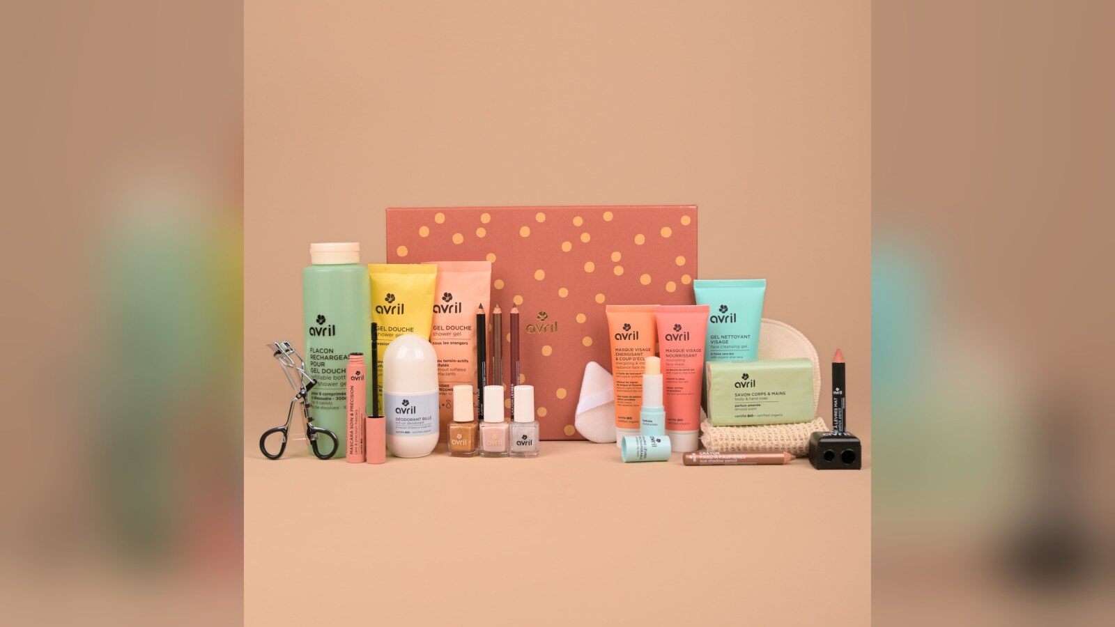 Le coffret du calendrier de l’Avent Avril 2026 entouré de ses produits : gels douche, masques, crayons, vernis et baume