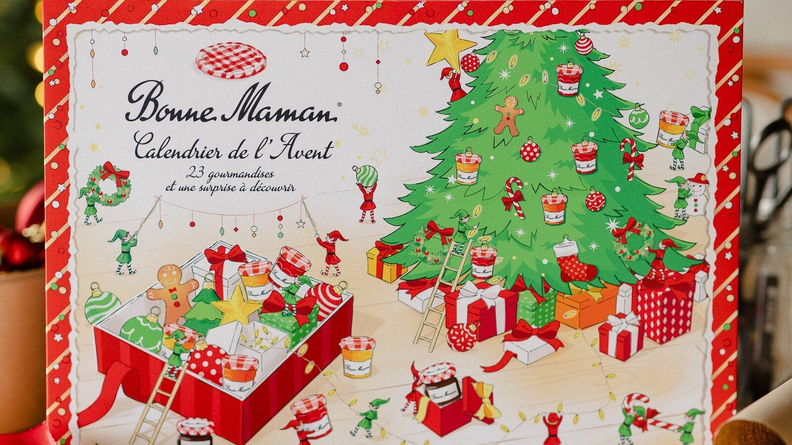Le calendrier de l’Avent Bonne Maman 2026 fermé, illustré d’un sapin de Noël, posé sur une table devant un sapin décoré