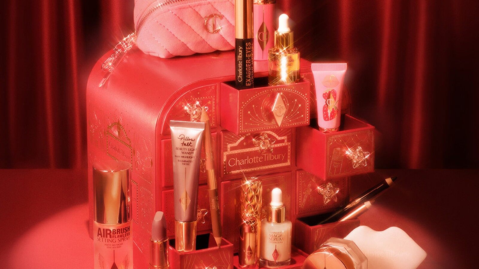 Le calendrier de l’Avent Charlotte Tilbury 2026 rouge à étoiles dorées entouré de ses produits sur fond de rideau rouge