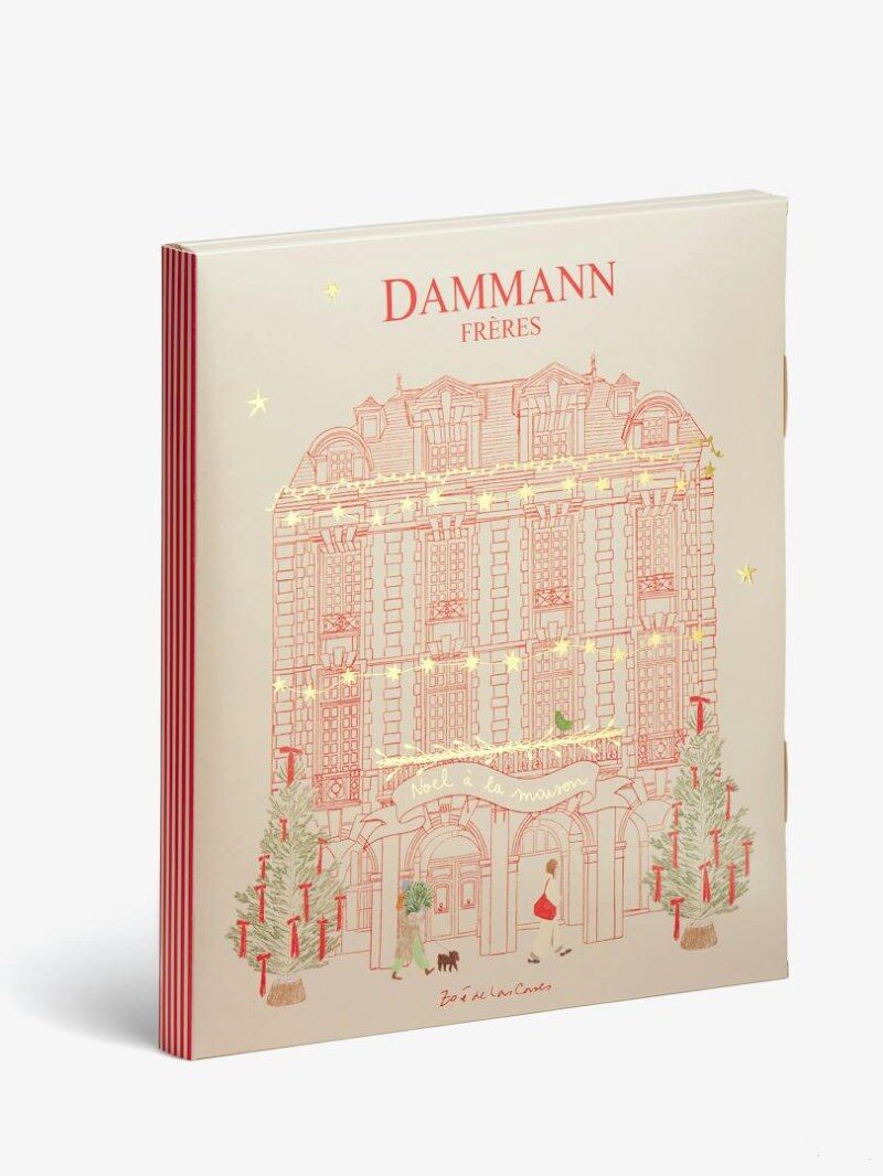 Le coffret du calendrier de l’Avent Dammann Frères 2026 vu de face, avec la façade d’un hôtel particulier dessinée en rouge et or, deux sapins et la mention Noël à la maison