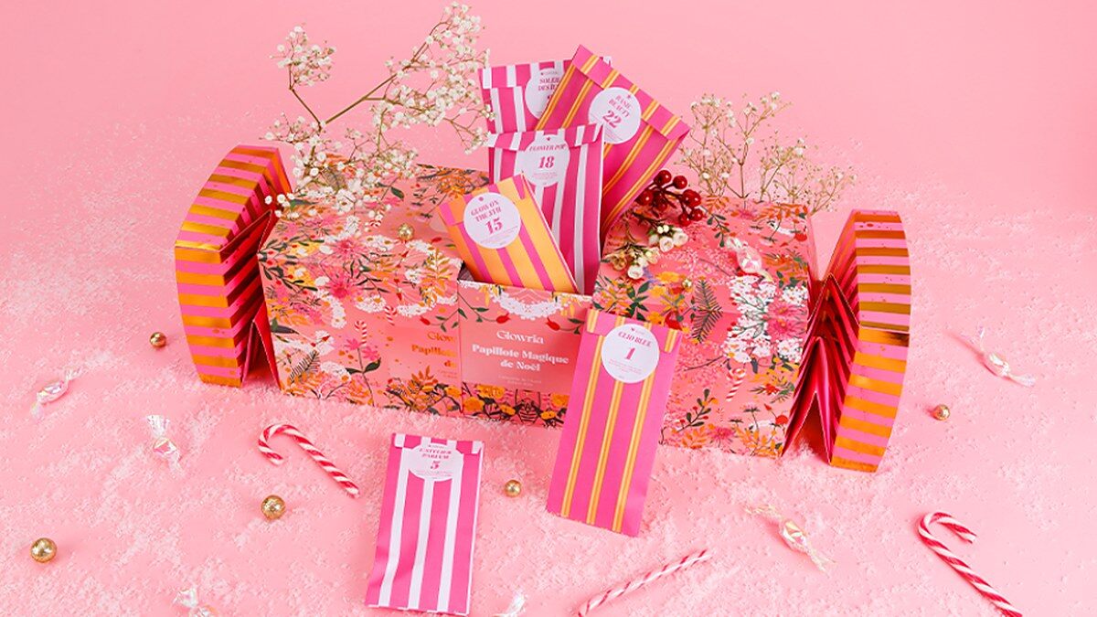 La papillote géante rose et dorée du calendrier de l’Avent Glowria 2026 posée au milieu de sucres d’orge et de branches de houx
