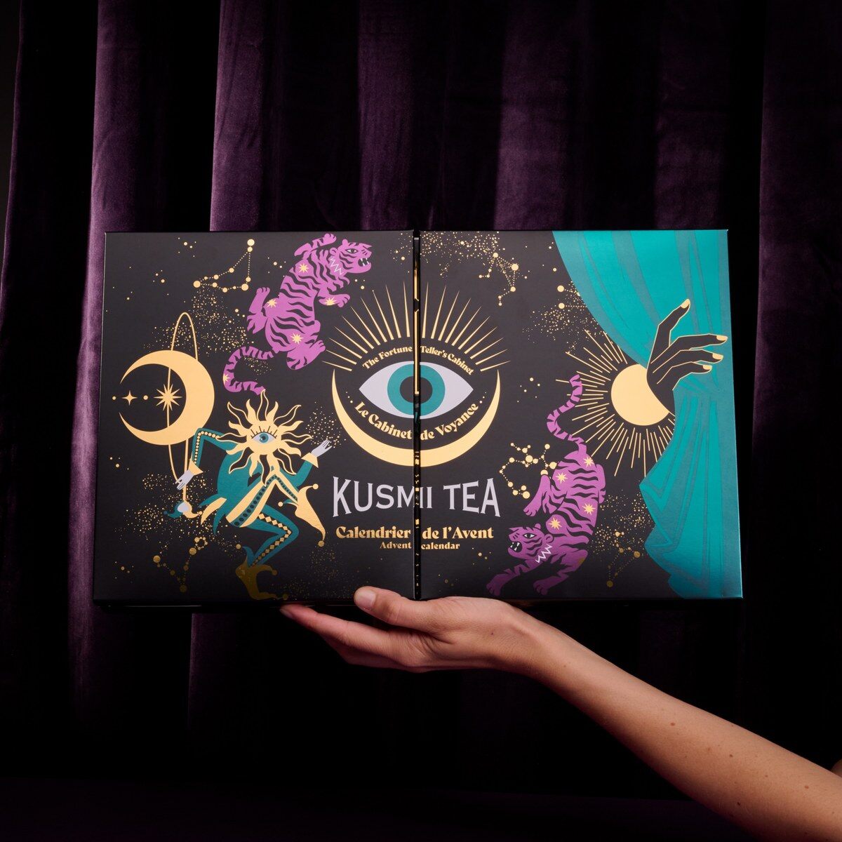 Une main présente le coffret fermé du calendrier de l’Avent Kusmi Tea 2026 noir et or