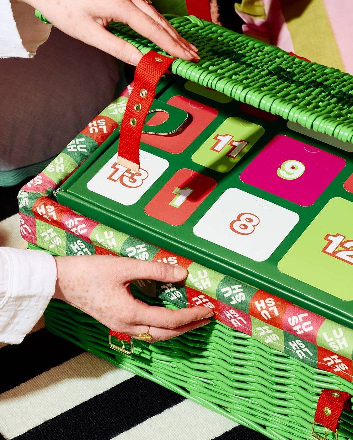 Deux mains ouvrent le panier en osier du calendrier de l’Avent Lush 2026 et découvrent les cases numérotées