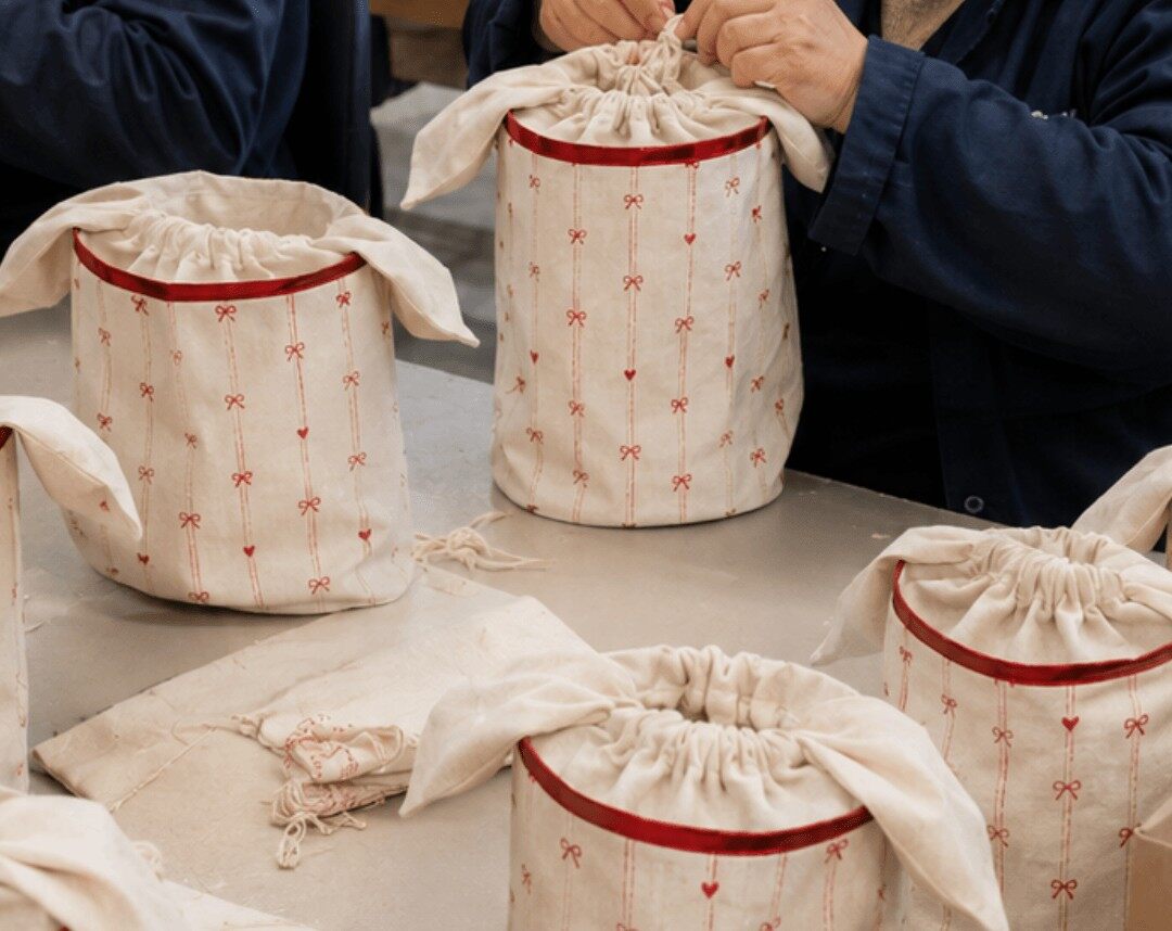 Des pochettes rayées roses et rouges numérotées dans un sac en toile à motifs de nœuds