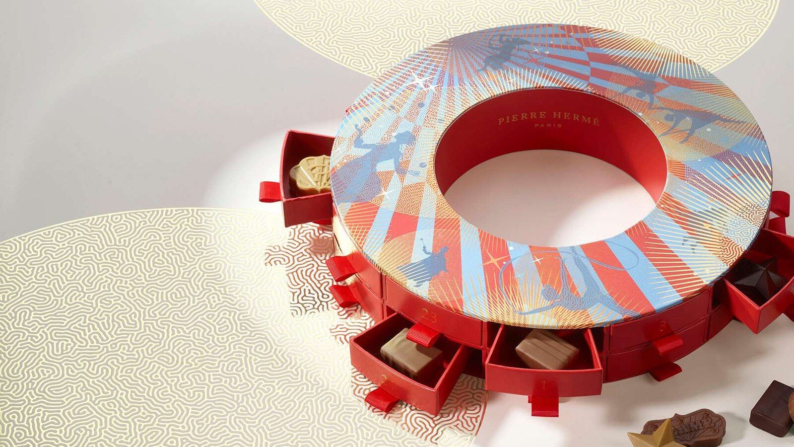 La couronne de l’Avent Pierre Hermé 2026 illustrée d’acrobates, tiroirs rouges ouverts sur des chocolats