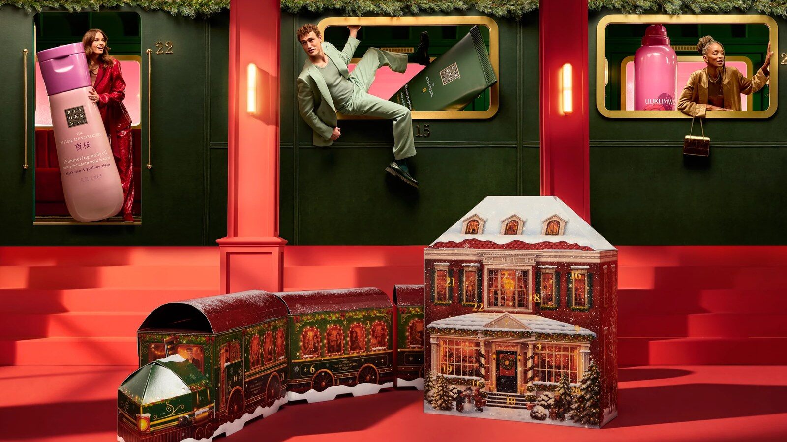 Les calendriers de l’Avent Rituals 2026 Classic en forme de maison et Premium en forme de train, devant un décor de wagon rouge