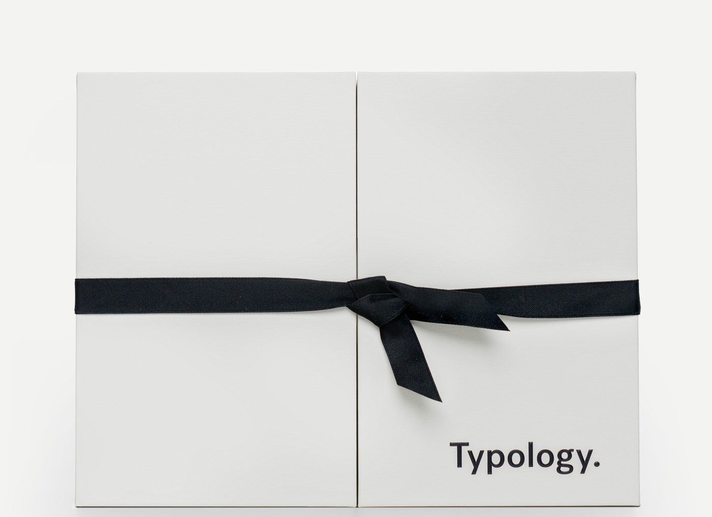 Le coffret fermé du calendrier de l’Avent Typology 2026, blanc avec un ruban noir noué
