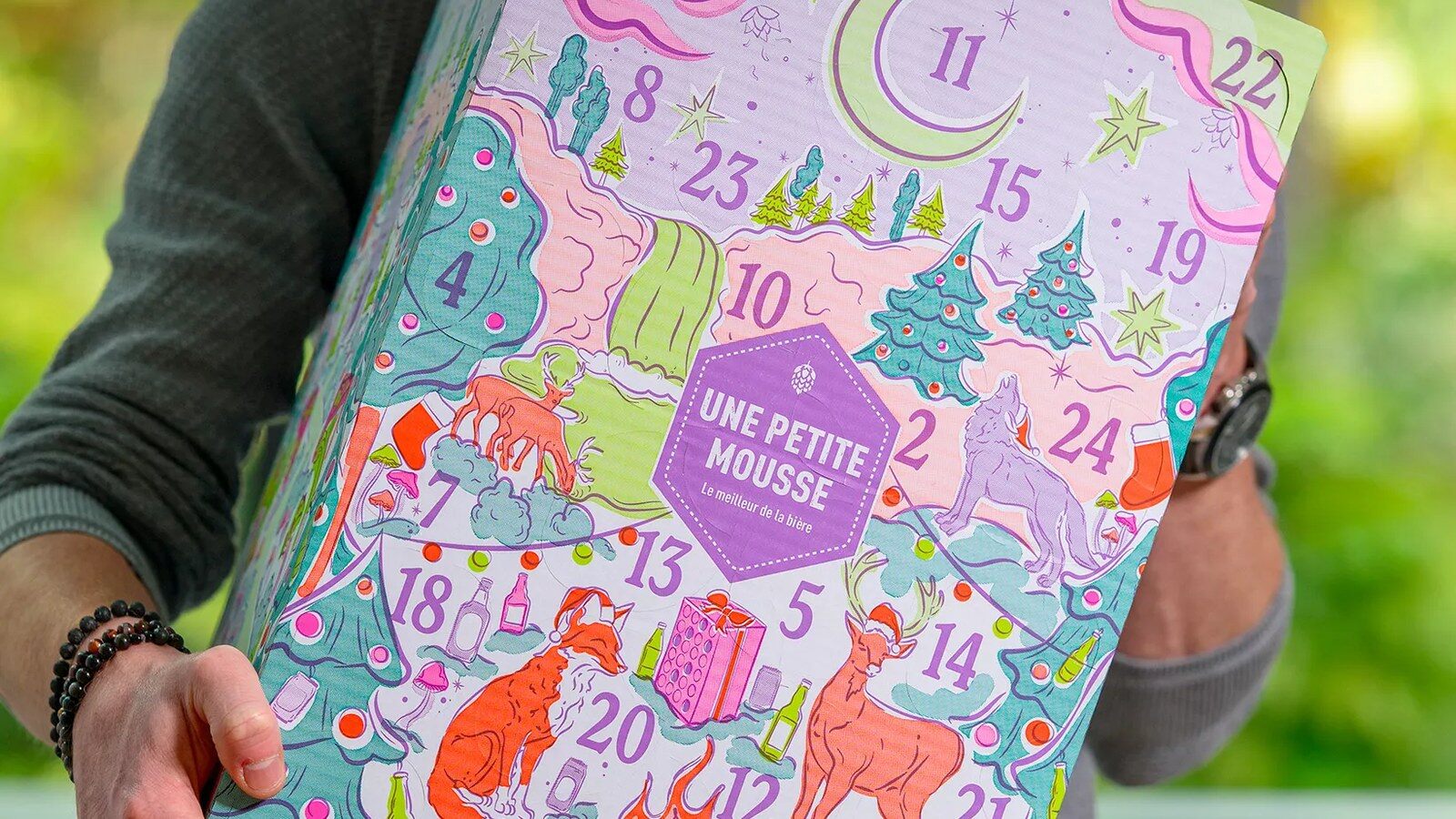 Un homme tient le calendrier de l’Avent bière illustré Une Petite Mousse 2026